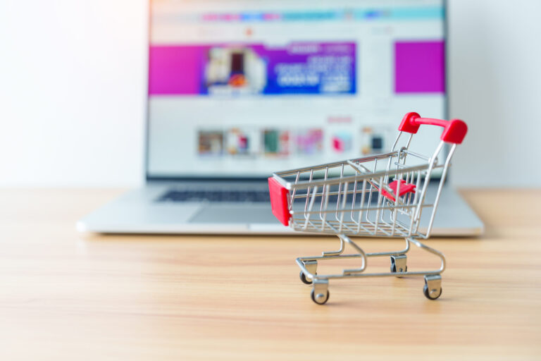 Shopping cart and laptop computer representing online marketplaces and e-commerce.