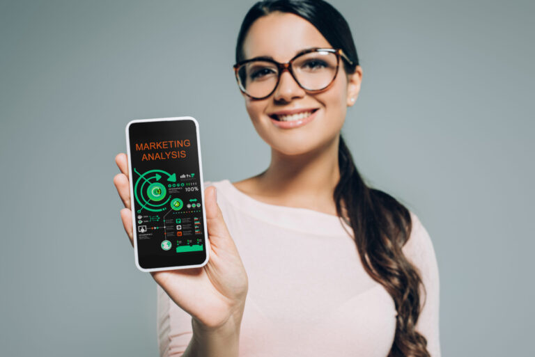 Woman smiling and showing smartphone with marketing analysis graphics.