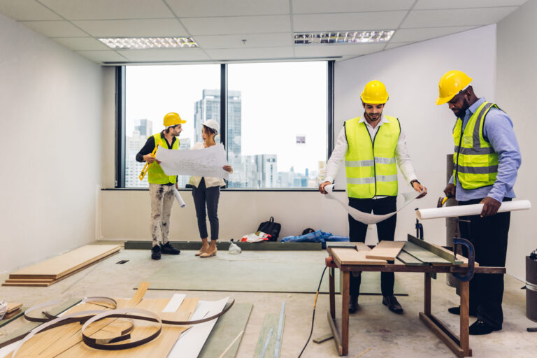 Engineering team reviewing building plan in office setting, construction project planning.