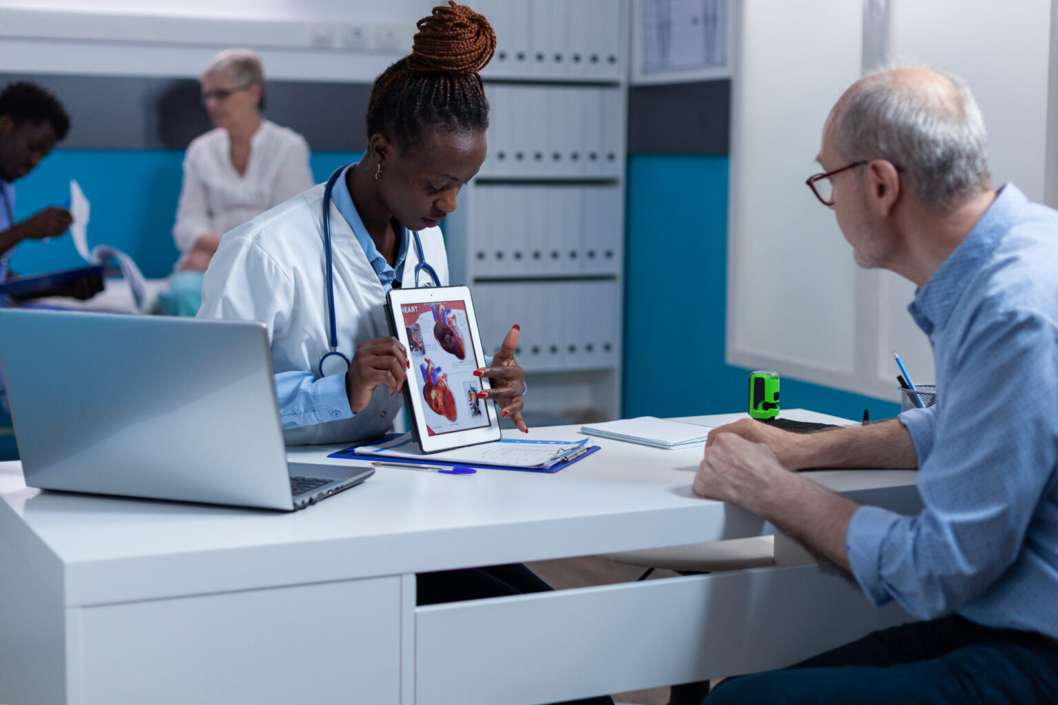 Cardiologist examining senior patient's heart health with tablet displaying anatomical image.